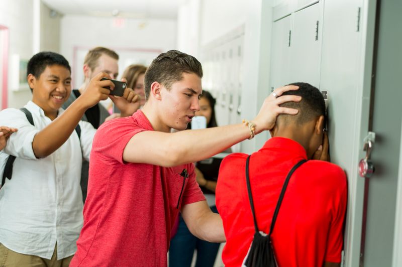 Boy bullying other boy while others are looking.